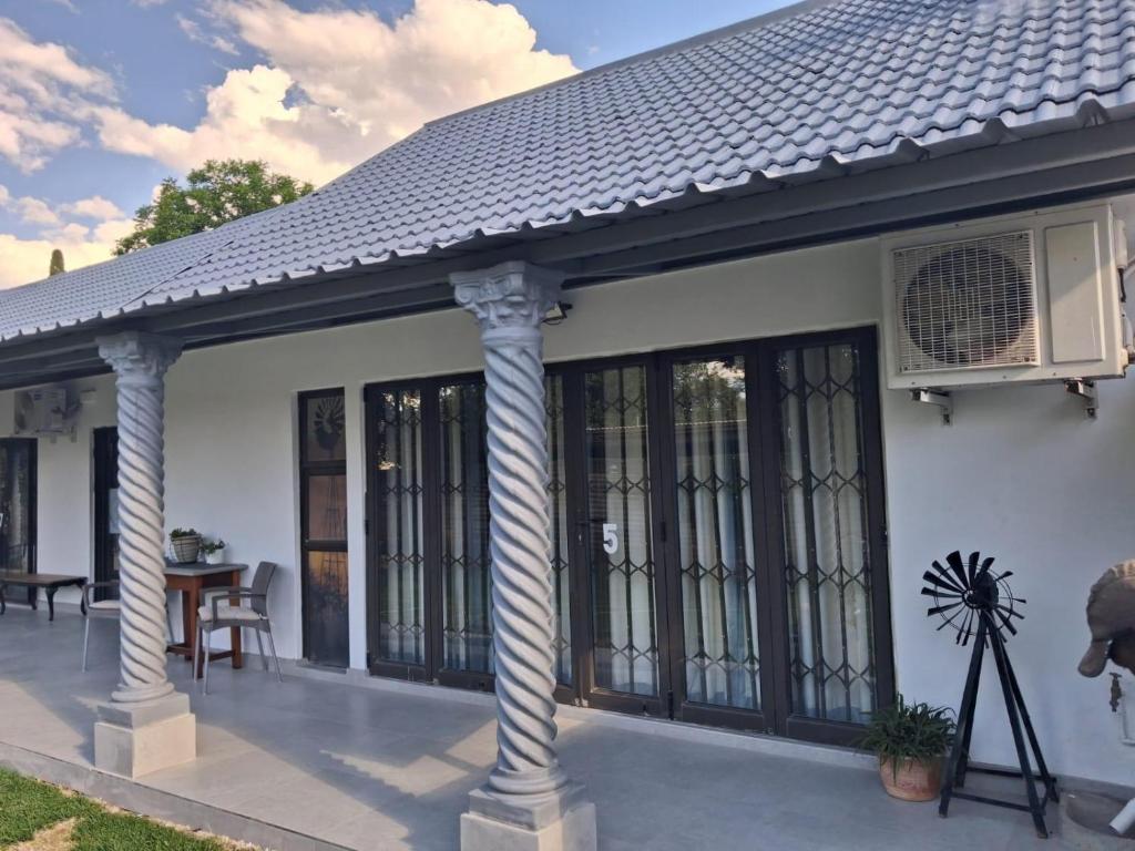 ein weißes Haus mit Säulen und einer Terrasse in der Unterkunft Juliet Rose Luxury Guesthouse B&B in Bloemfontein