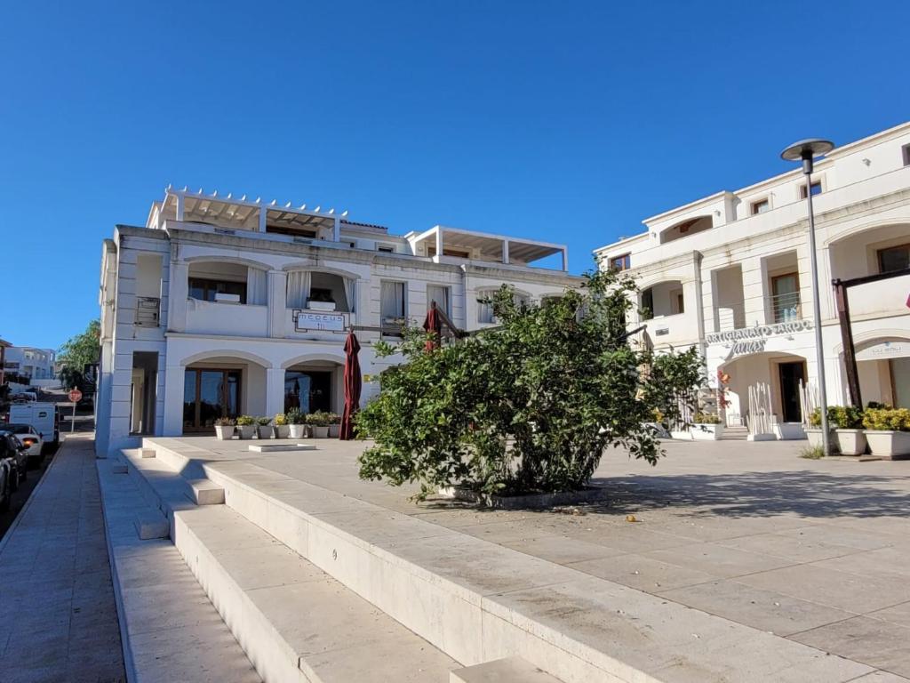 Un edificio blanco con un árbol delante. en H41 Attico in centro, en Budoni