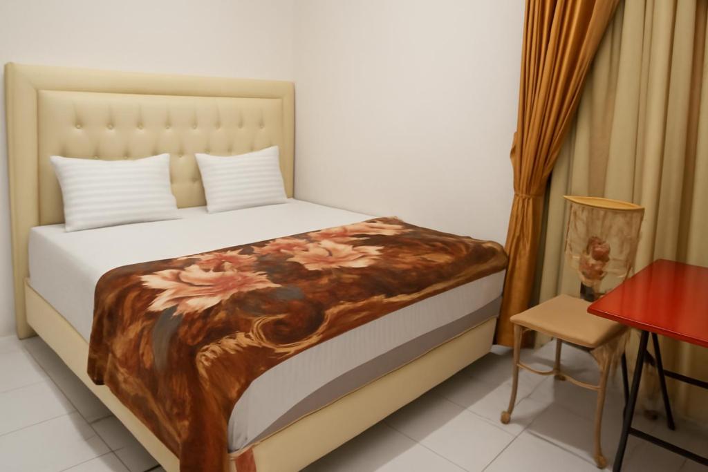 a bedroom with a bed with a flower blanket on it at Luxe5 Inn Hj Hasnah Hasan in Takengon