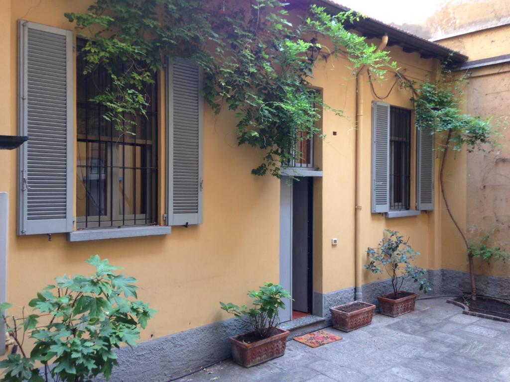 un bâtiment jaune avec des fenêtres et des plantes en pots dans l'établissement Olona Place, à Milan