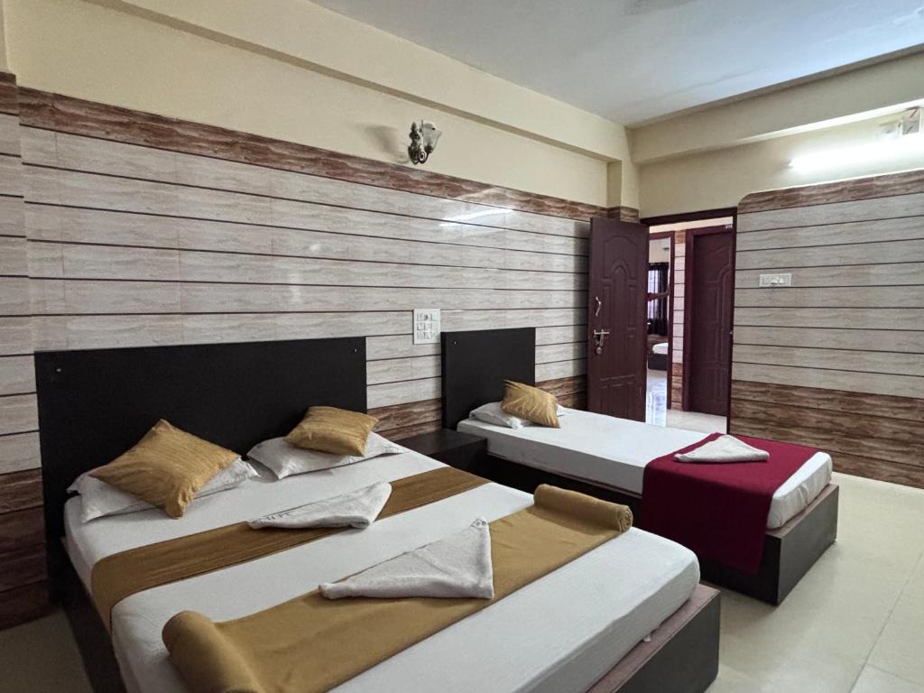 Dos camas en una habitación con paredes de madera. en Yammuna Vihaar Tourist Home, en Kollūru