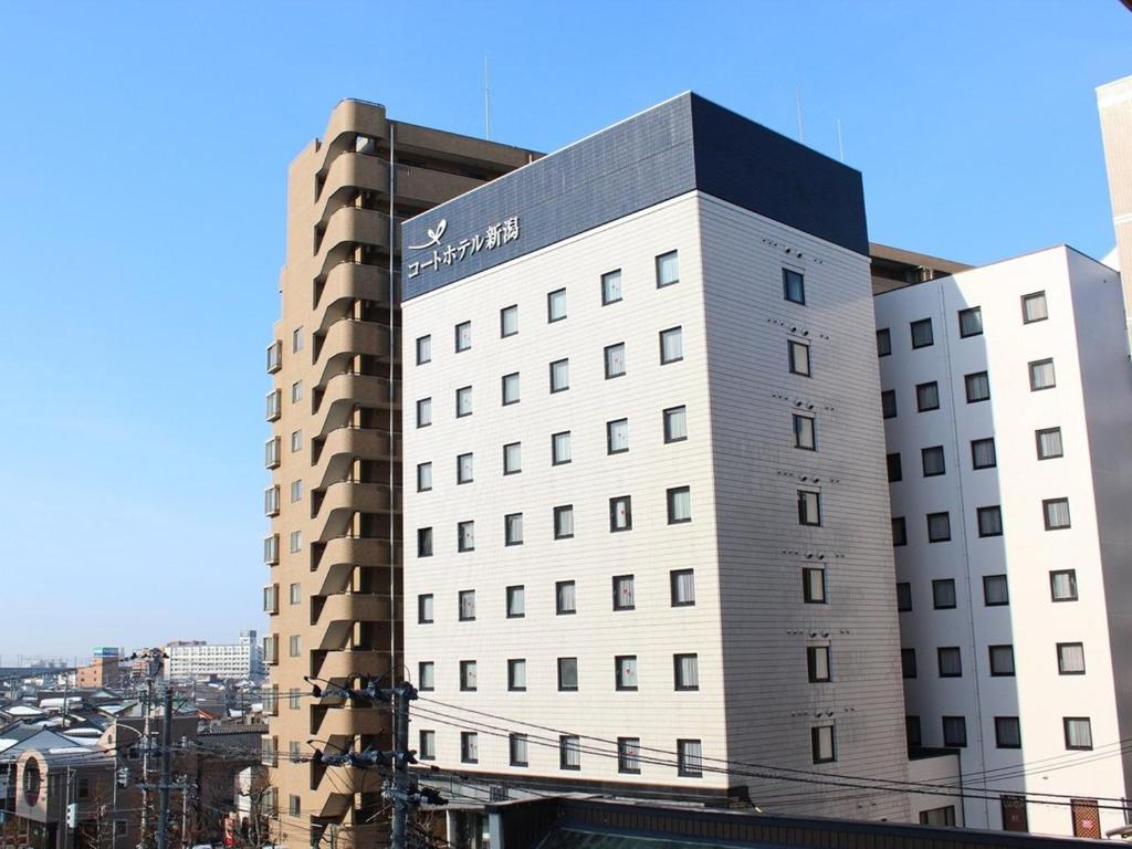 a white building with a sign on the side of it at Court Hotel Niigata in Niigata