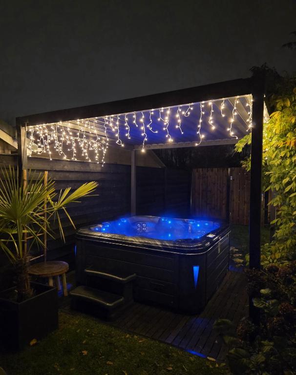 a hot tub under a pergola with lights at "Huisje op de Veluwe" met privé Jacuzzi en Bar! in Ermelo