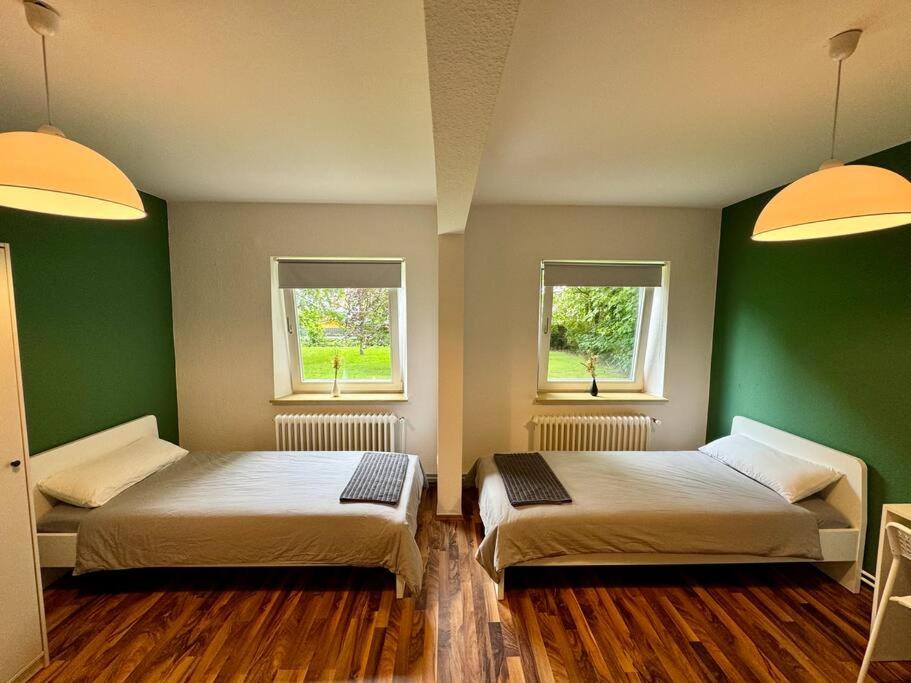- 2 lits dans une chambre dotée de murs verts et de fenêtres dans l'établissement Complete All Inclusive Apartment+Netflix, à Wilhelmshaven