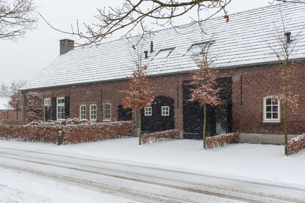 un bâtiment en briques rouges avec de la neige au sol dans l'établissement B&B De Ouw Skuur, à Oirschot