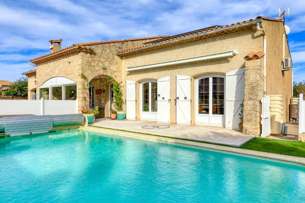 Villa Angelo - Olive Verte في Saint-Thibéry: منزل به حوض سباحة أمام المنزل