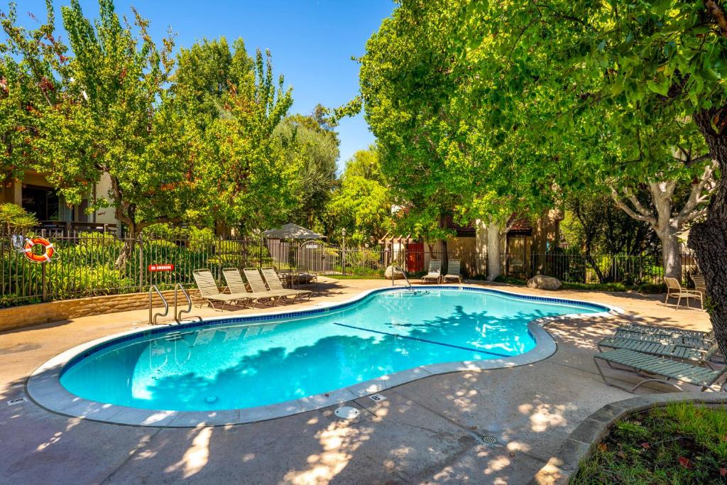 Warner Center Plaza One HeliportにあるElsa Houseの椅子と木々のある庭のスイミングプール