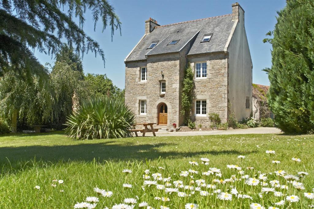 an old stone house with a field of flowers at Domaine le Puits de Jeanne in Plouégat-Moysan