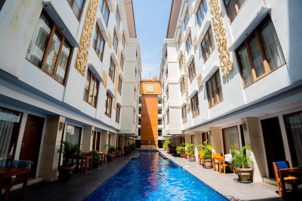 a courtyard of a building with a swimming pool and a clock tower at Bali Sun Tropical Hotel & Spa - formerly The Sun Hotel & Spa Legian in Legian