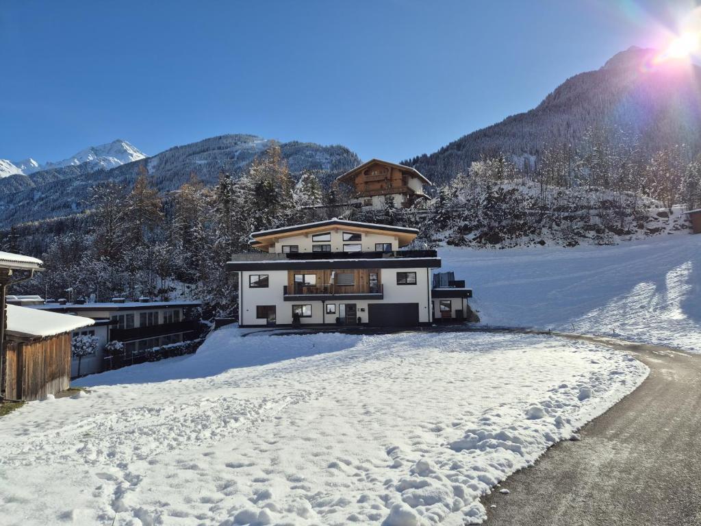 a house in the snow in front of a mountain at Mountainsurf Apartments in Finkenberg