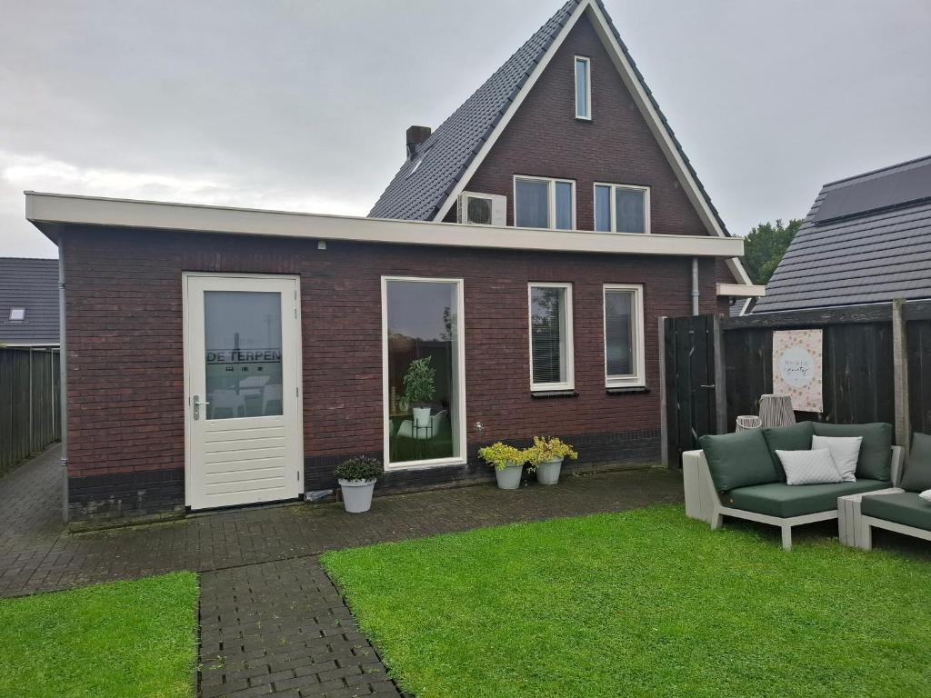 a red brick house with a patio with two chairs at B&B De Terpen in Dokkum