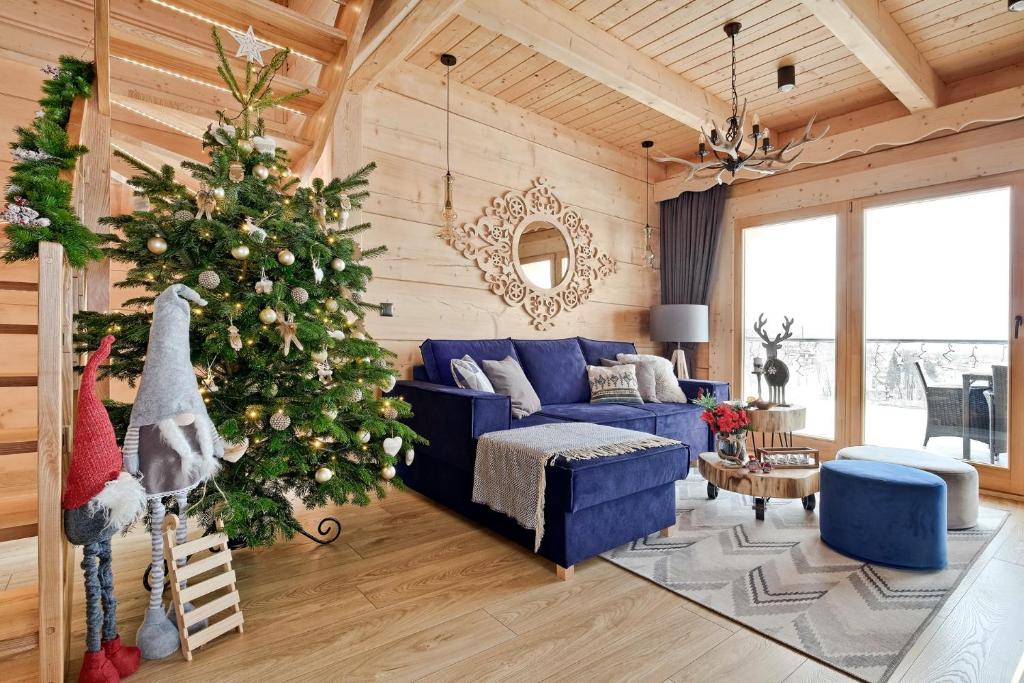 a living room with a christmas tree and a blue couch at Osada Bachledzki Wierch Odkryj Zakopane in Zakopane
