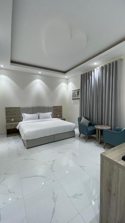 a bedroom with a large bed and a blue chair at غرفه - واڤا in Tabuk
