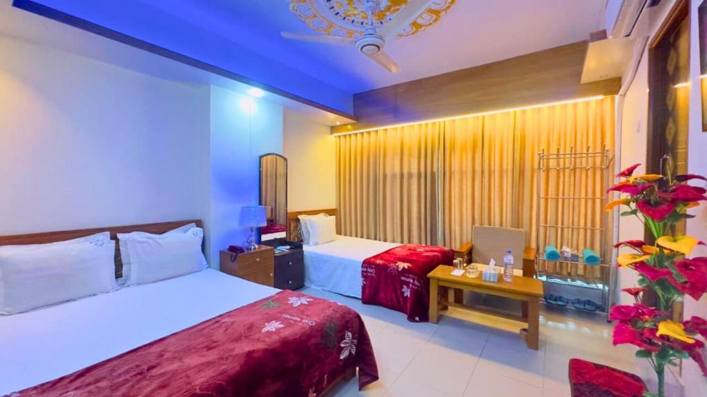 Un dormitorio con dos camas y una mesa con un portátil. en Hotel Blue Sky Mirpur, en Dhaka