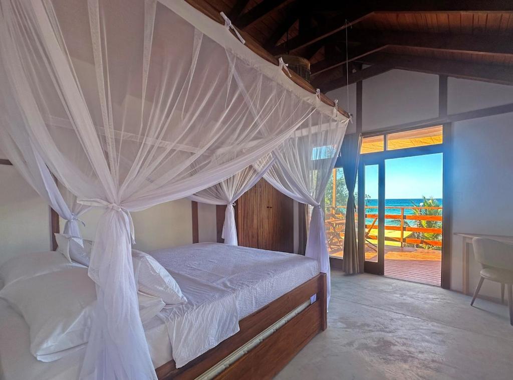 1 dormitorio con cama con dosel y vistas al océano en Índico Breeze, en Praia do Tofo