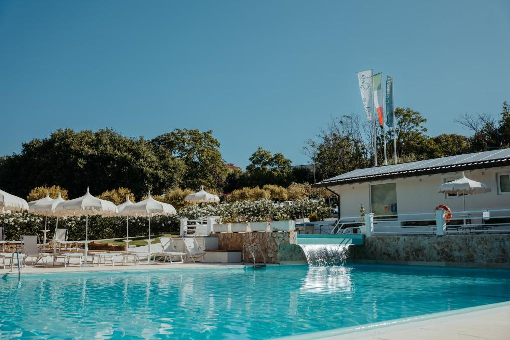 a swimming pool with chairs and umbrellas at Green Garden Village in Sirolo