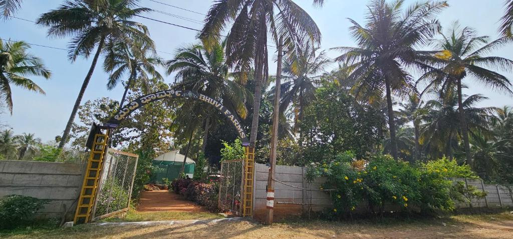 マイソールにあるBhuvi farmsのヤシの木を背景にした庭園への門