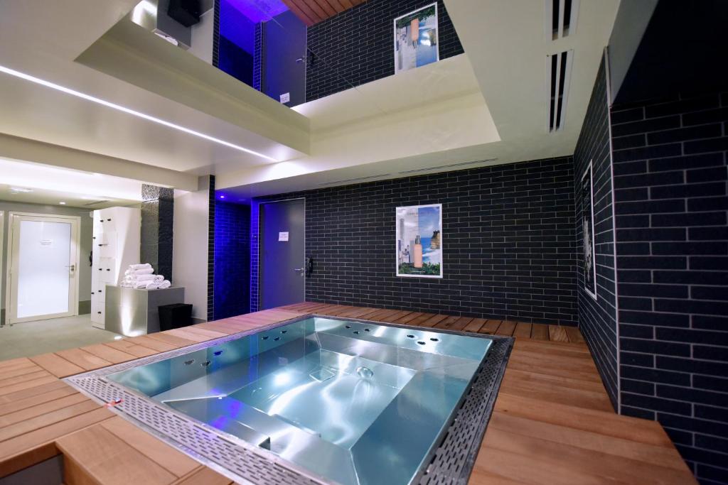 a hot tub in a room with a brick wall at Kyriad Hotel Dijon Centre Gare in Dijon