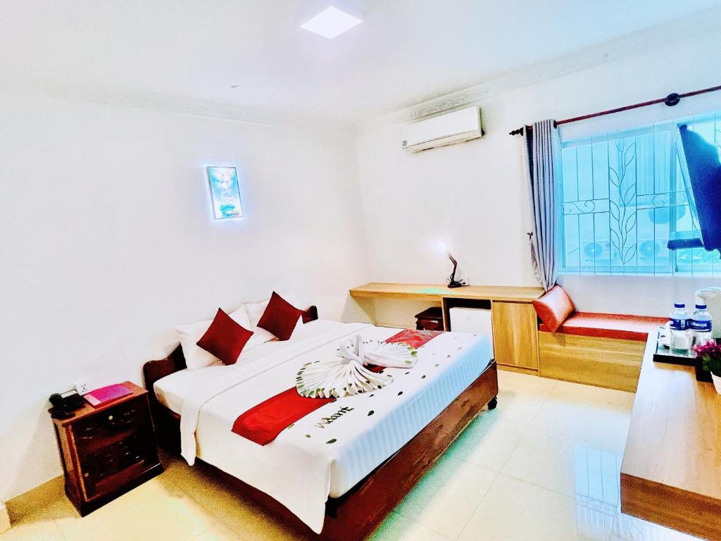 a bedroom with a bed and a desk and a window at The One by Nika in Siem Reap