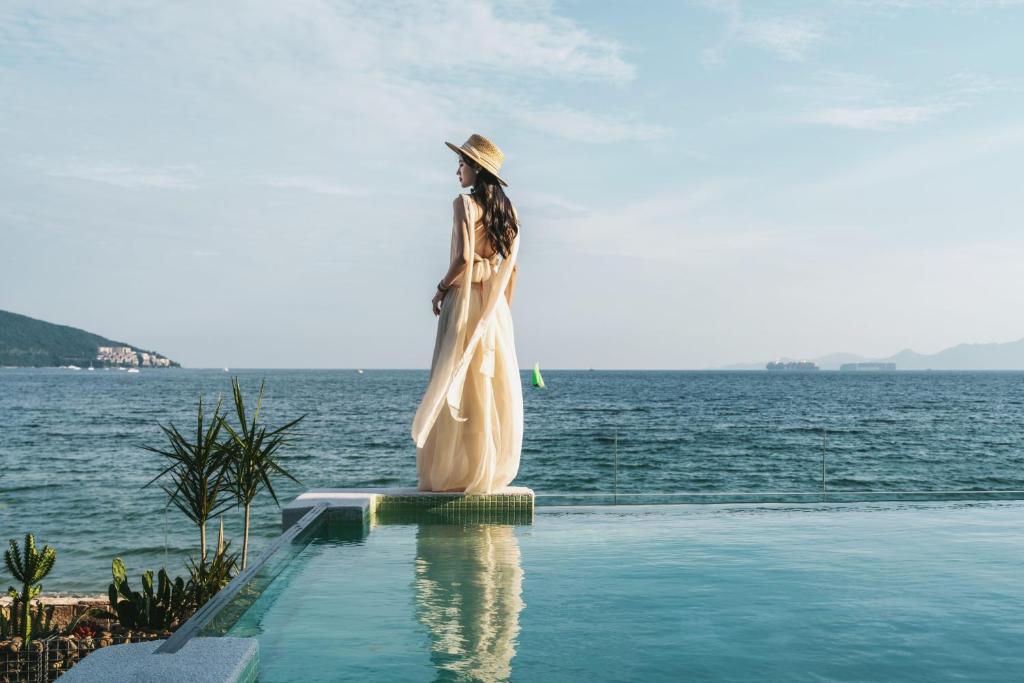 a woman standing next to a swimming pool next to the water at Xi'an seascape meisu-MOMOO Sea in Longgang