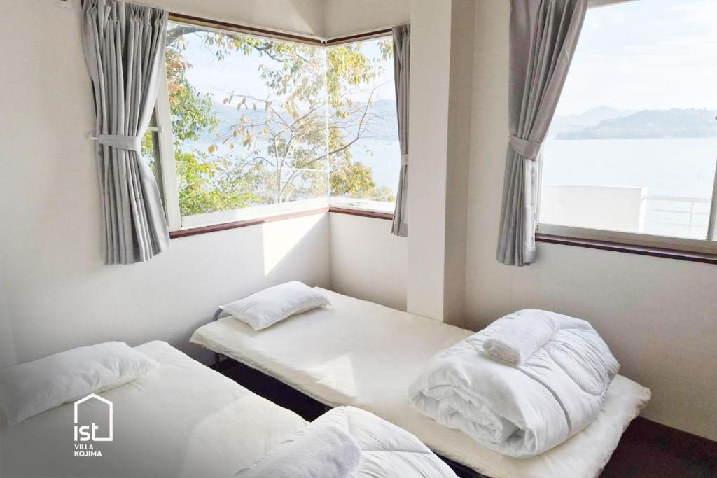 zwei Betten in einem Zimmer mit Fenster in der Unterkunft ist villa 06 Private Beachfront Sleeps 16 in Wada