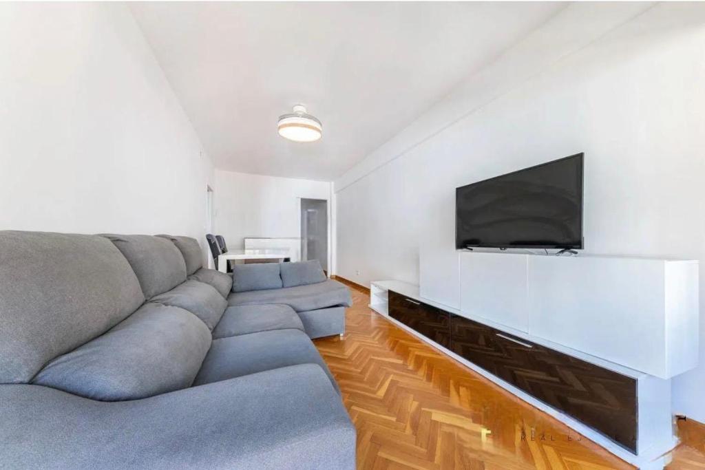 a living room with a gray couch and a flat screen tv at Apartamento en 1ª línea de playa con parking privado in El Campello