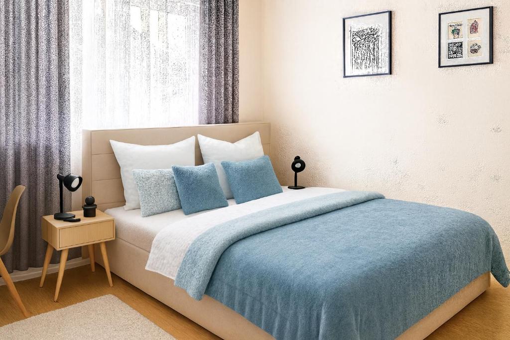 a bedroom with a bed with a blue blanket and a window at Wohnung mit Balkon in Wilnsdorf