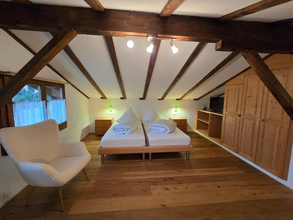a bedroom with a bed and a chair in a room at Charming Louisa Zimmer Roof - KEINE KÜCHE in Rueras