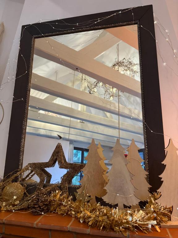 Un espejo con adornos navideños sobre una repisa. en Le Parc du Séquoia & SPA proche Colmar et Riquewihr, en Ostheim