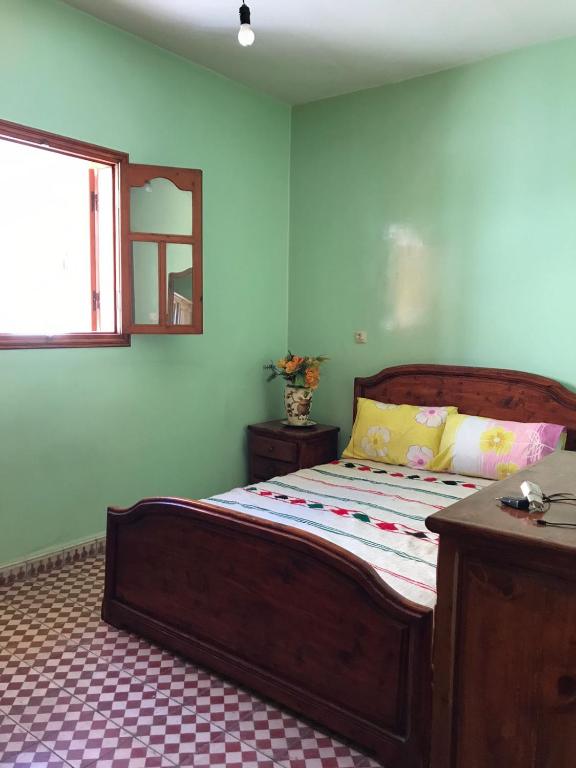 a bedroom with a bed with a wooden frame and a window at LoveWave House in Agadir