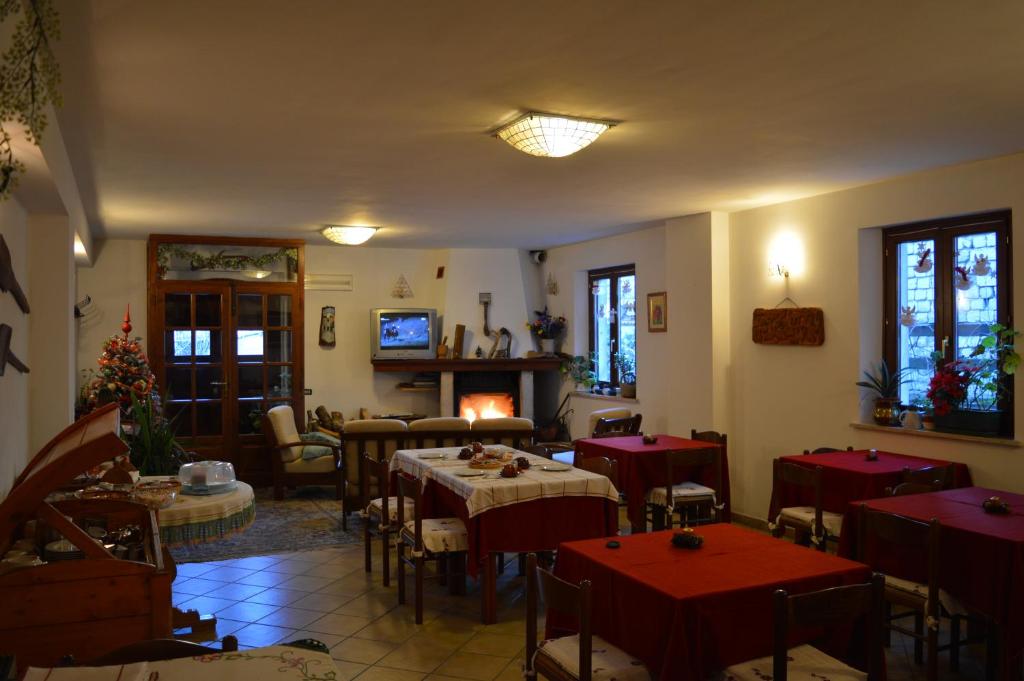a restaurant with red tables and chairs and a fireplace at B&B Dulcamara in Pescasseroli