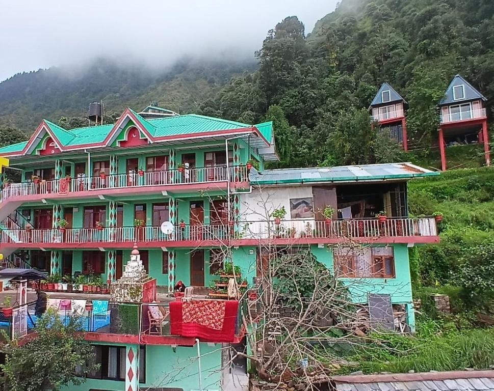 Una casa verde con balcones rojos en una montaña en Dreamcatcher Homestay, en McLeod Ganj