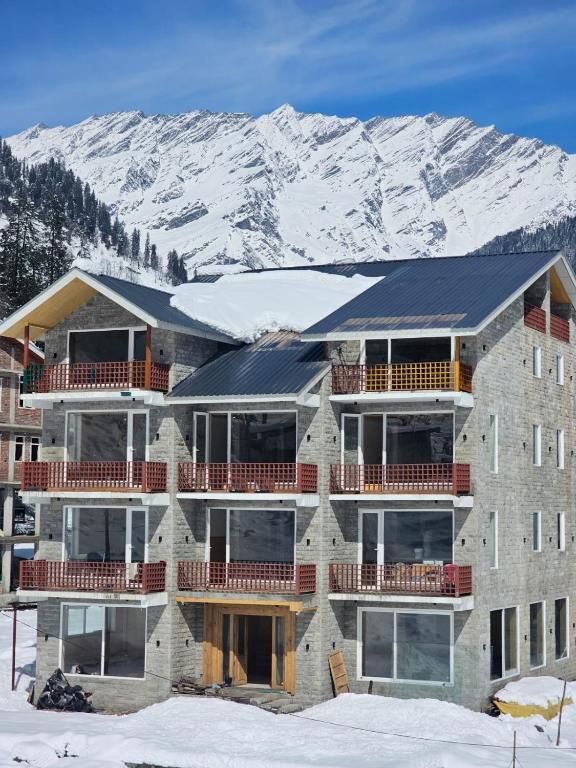 a building with snow covered mountains in the background at Hotel Patalsu in Palchān