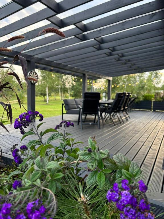 a wooden deck with chairs and a table and purple flowers at Laumiņas in Pavasari