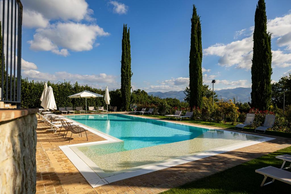 a swimming pool in a resort with chairs and trees at Agriturismo La Corte dei Cavalieri in Montefalco