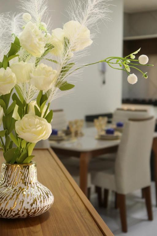a vase filled with white flowers on a table at CS1 - Ampla Casa com ArCond e Lazer Completo in Juazeiro do Norte