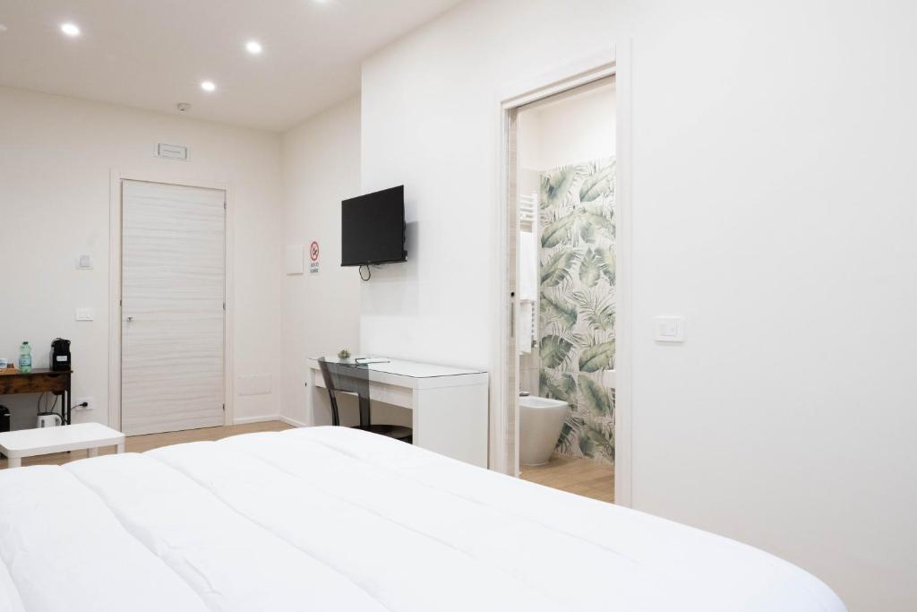 a white bedroom with a bed and a desk and a television at Happy Boutique Home Ercolano in Ercolano
