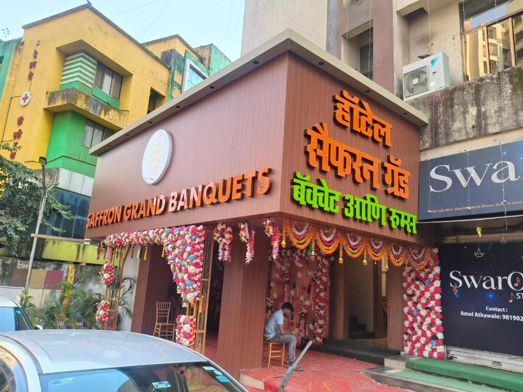een gebouw met borden aan de kant van een straat bij Hotel Saffron Grand Thane in Thane