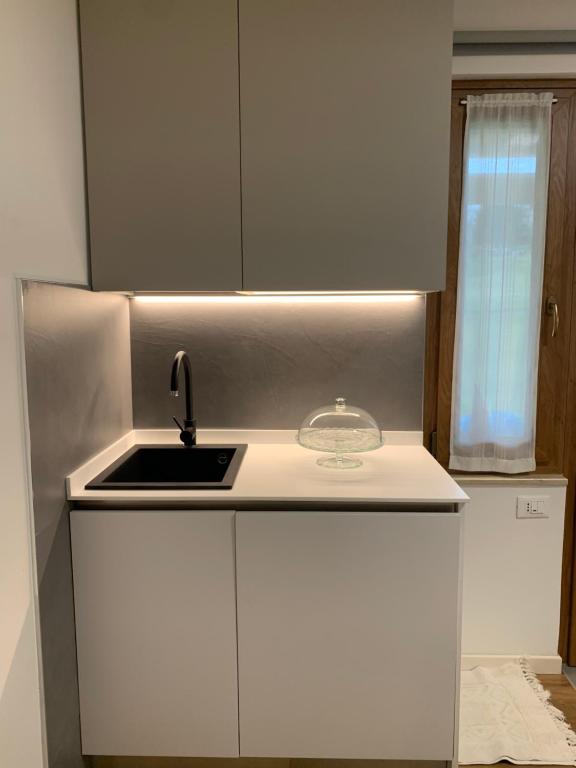 una cucina con mobili bianchi, un lavandino e una finestra di Casa S. Caterina a Piaia