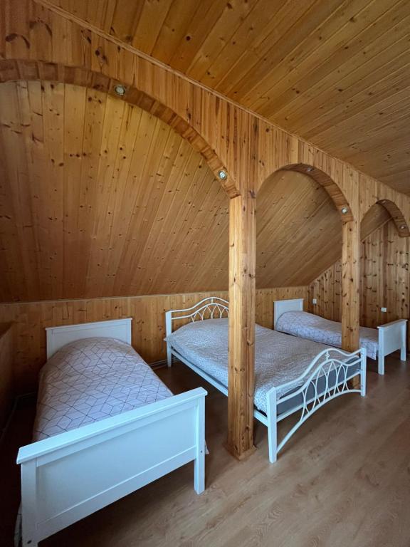 deux lits dans une chambre aux murs en bois dans l'établissement KRI Holiday House, à Alūksne