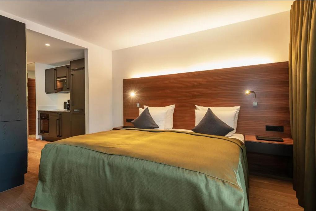 Un dormitorio con una cama grande con cabecero de madera. en AlpenParks Hotel & Apartment Taxacher, en Kirchberg in Tirol