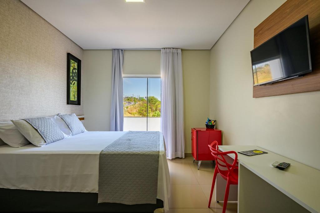 a hotel room with a bed and a window at OYO Tropical Confort Hotel, Brasilia in Brasília