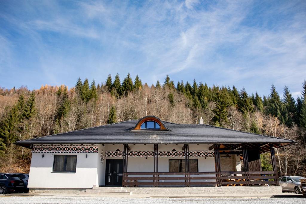 a white building with a black roof and trees at Pensiunea Lizucăi - Ciocănești in Valea Stînei