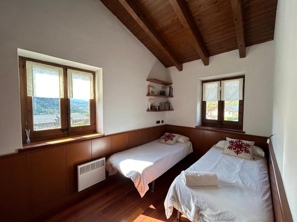 ein Schlafzimmer mit zwei Betten und zwei Fenstern in der Unterkunft Casa Riu in Riu de Cerdanya