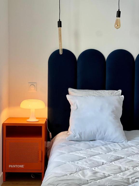 ein Bett mit einem blauen Kopfteil und einem Tisch mit einer Lampe in der Unterkunft Les Couleurs du Lac in Gérardmer