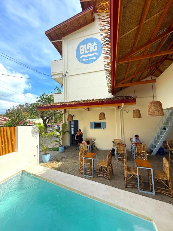 a person sitting at a table next to a pool at Blau Hostel in El Nido