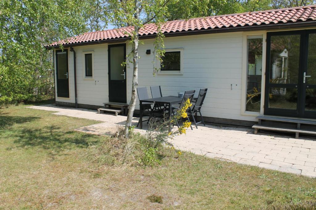 a house with a table and chairs in front of it at Heitje 166 in Den Burg
