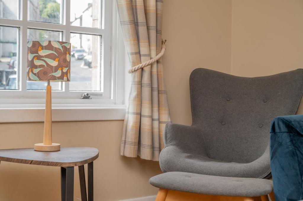 ein Wohnzimmer mit einem Stuhl und einem Fenster in der Unterkunft Bow Apartment in Stirling