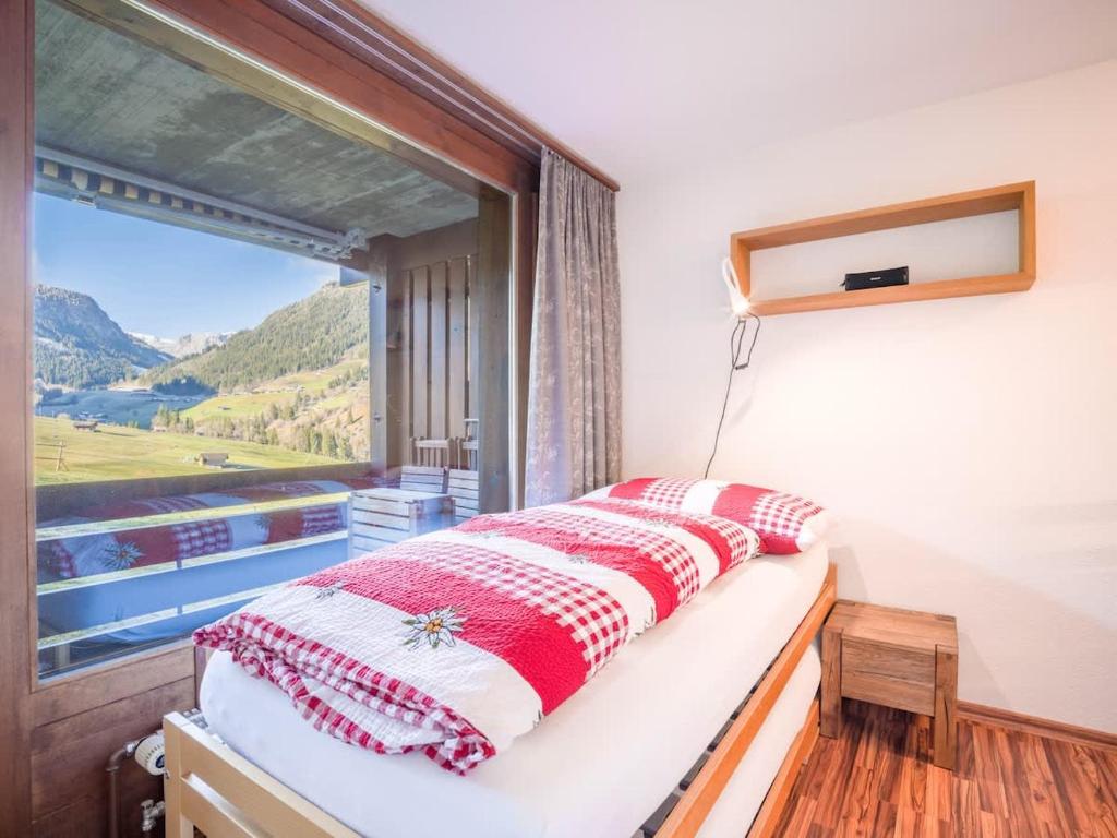 a bed in a room with a large window at Alpine Studio for 4 in Nature Parc balcony&Parking in Horboden