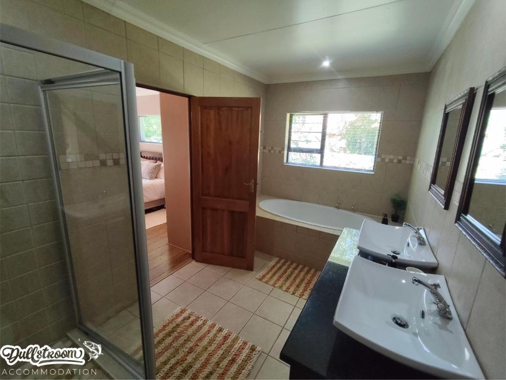 een badkamer met een douche, een wastafel en een bad bij Central Park in Dullstroom